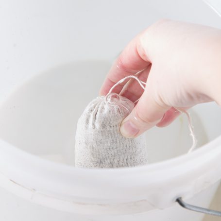 placing manure tea fertilizer bag in bucket of water