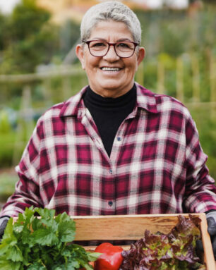 Senior woman holding fresh vegetables with garden in the backgro