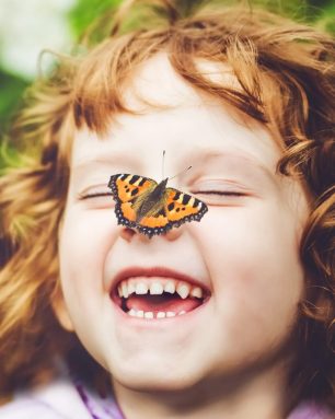 Laughing girl with a butterfly on his nose.